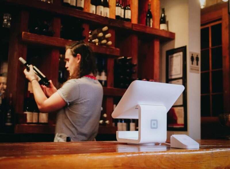 Mann in einer Weinbar prüft sorgfältig das Etikett einer Weinflasche. Symbolbild für Mitarbeitermotivation steigern, Produktivität steigern
