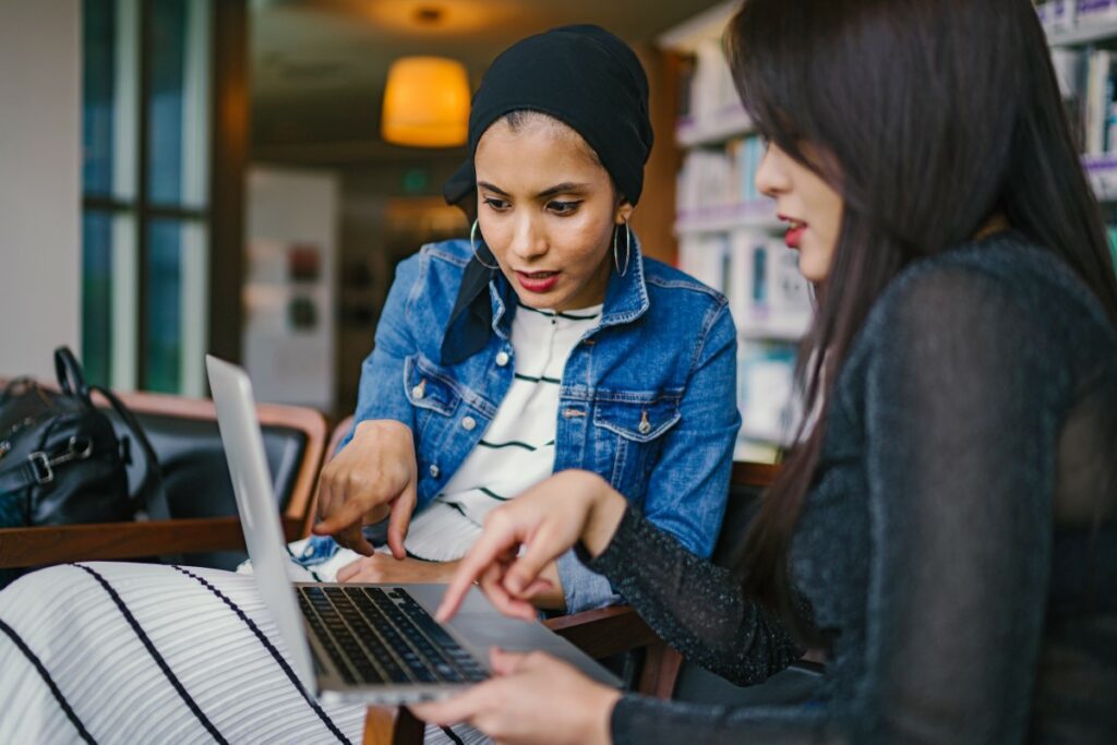 Zwei Frauen blicken gemeinsam auf einen Laptop Bildschirm und suchen neue Mitarbeiter