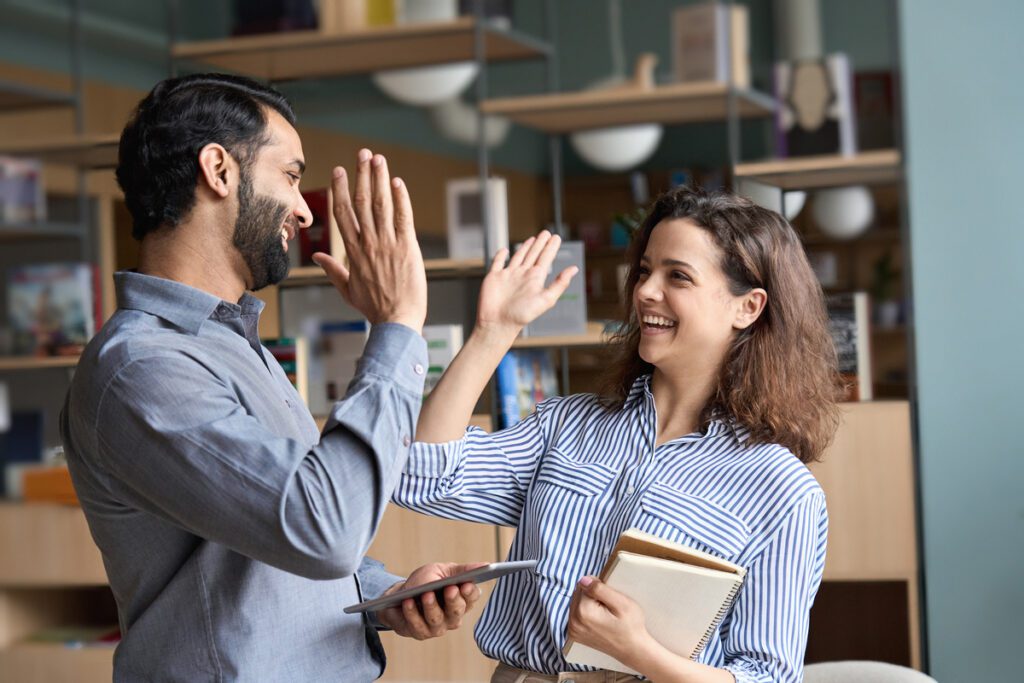 Kollege und Kollegin lachen und gegen sich High Five