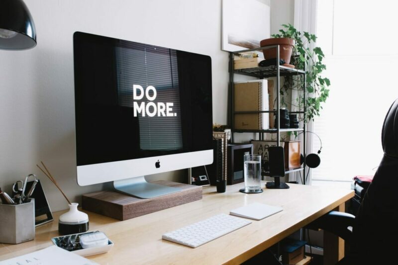 Schreibtisch, Arbeitsplatz. Auf dem Bildschirm der Schriftzug &quot;Do more&quot;. Symbolbild für Mitarbeitermotivation steigern, Produktivität steigern