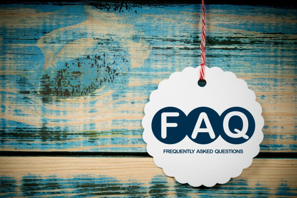 Holzplanken mit abgeblätterter blauer Farbe, davor eine weiße Plakette mit den Buchstaben FAQ