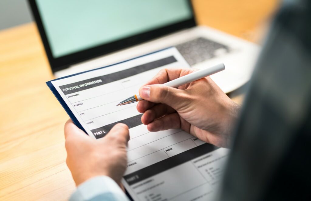 Fragebogen zur Mitarbeiterzufriedenheit wird von einer Person ausgefüllt, die einen grauen Stift in der rechten Hand hält