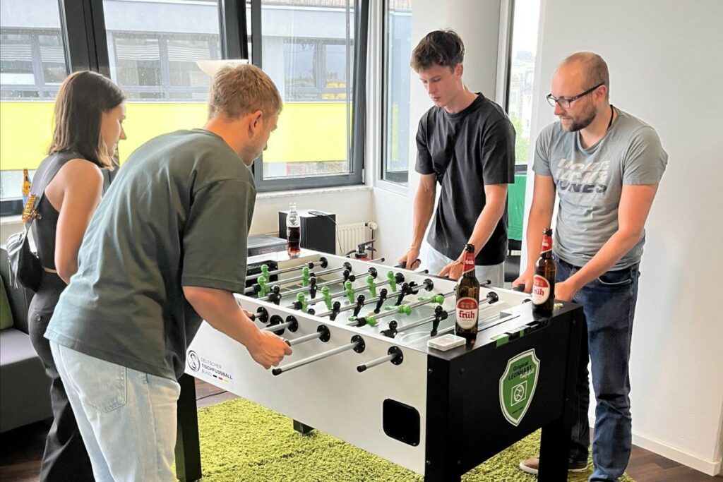 Vier Honestly Mitarbeiter spielen Tischkicker in der Pause