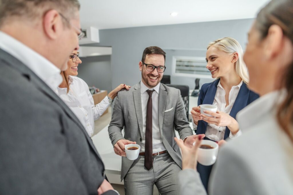 Kollegen machen gemeinsam Kaffeepause, unterhalten sich und lachen